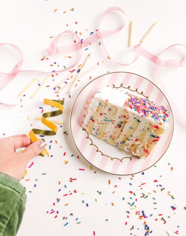 slice of birthday cake with pink ribbon and confetti