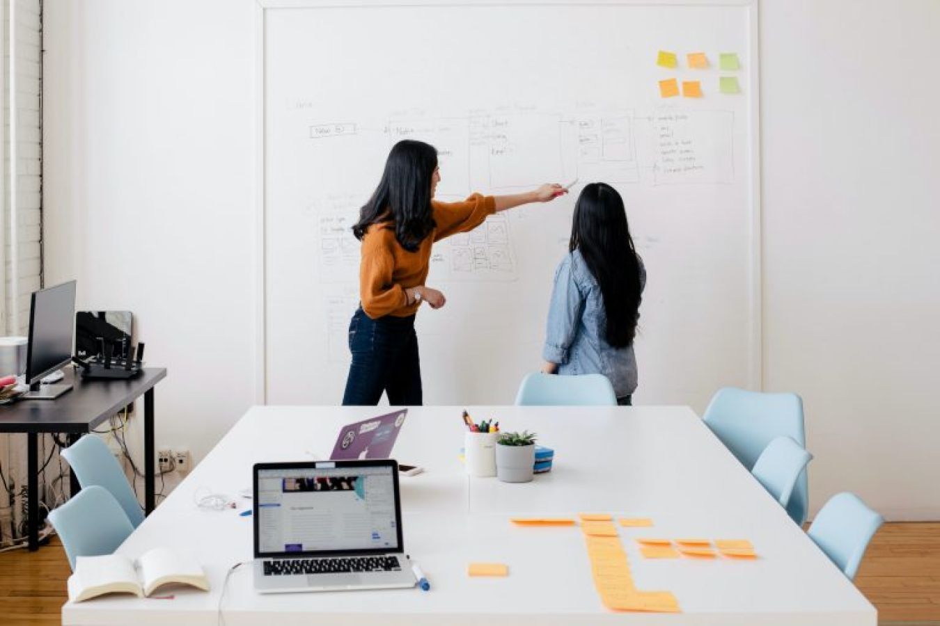Two women discussing diagram on whiteboard