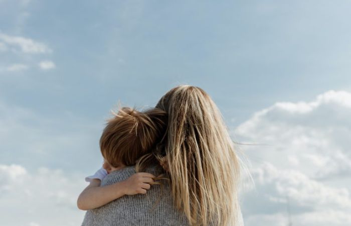 Back of woman carrying child with view of sky