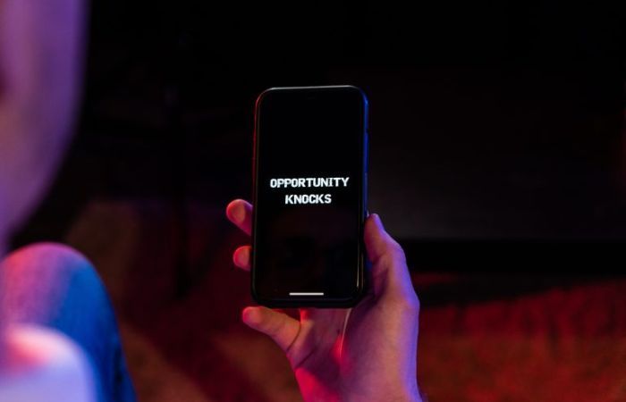 Hand holding mobile phone with 'Opportunity Knocks' on screen